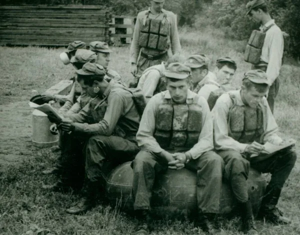 Retro-Foto zeigt junge Männer (Soldaten) während der Sommerzeit. Soldaten posieren mit Schwimmgurten (Weste) und setzen sich auf das Schlauchboot. Oldtimer-Fotografie. — Stockfoto