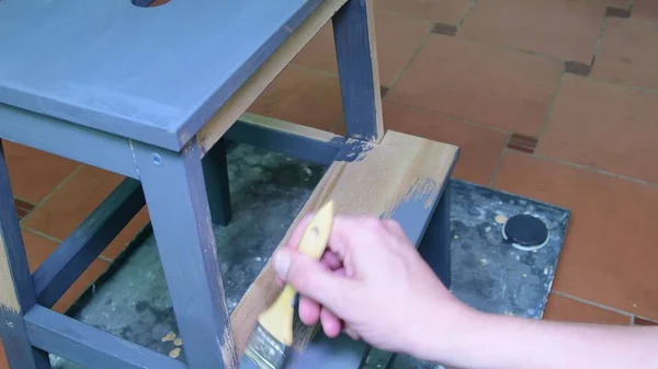 Mans hand paints the furniture step stool . Gray coating. Painting step stool with grey color — Stock Photo, Image