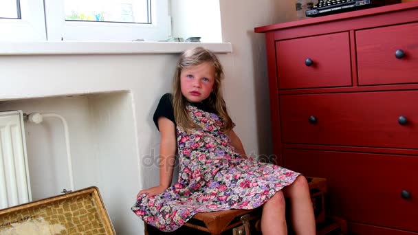 Το χαριτωμένο μικρό κορίτσι κάθεται σε vintage βαλίτσες και αναμένει την έναρξη των διακοπών. Smalll κορίτσι φοράει ανθοφορία φόρεμα. Ταξιδεύοντας έννοια — Αρχείο Βίντεο
