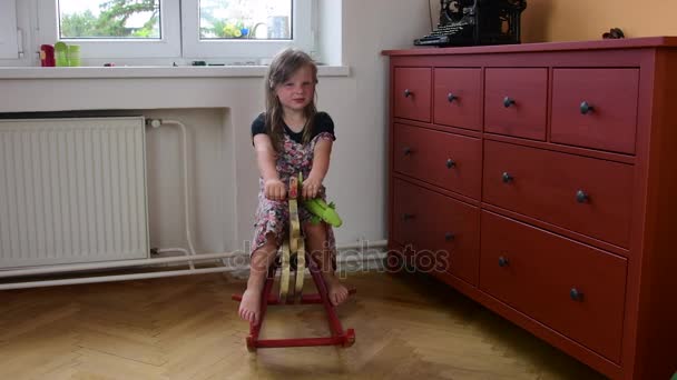 Linda niña baila y salta en una cama. Pequeña niña lleva vestido de flores. Concepto de infancia — Vídeos de Stock