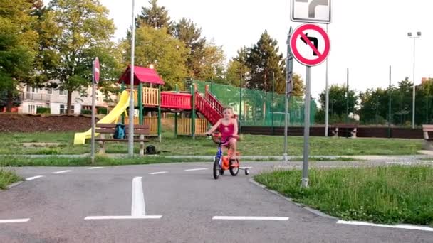 Holka jede na kole na hřiště dopravní. Malá holčička na kole v létě — Stock video