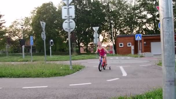 Fille monte le vélo à la circulation de terrain de jeu. Petite fille à vélo en été — Video