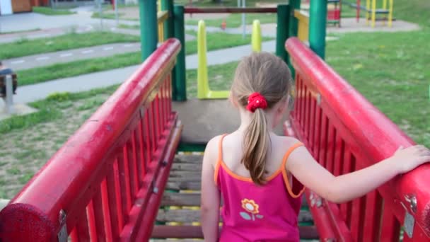 Vista della ragazza va sul ponte di corda nel playset al parco giochi — Video Stock