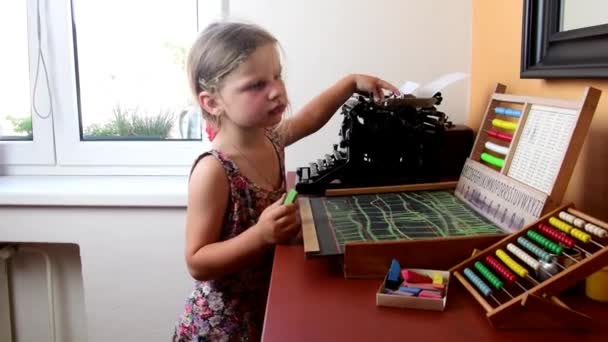 Menina doce brinca com ábaco e escreve no quadro negro com giz. Conceito pré-escolar, conceito infantil. Abacus de brinquedo com alfabeto checo e máquina de escrever vintage. Menina bonito como pré-escolar — Vídeo de Stock