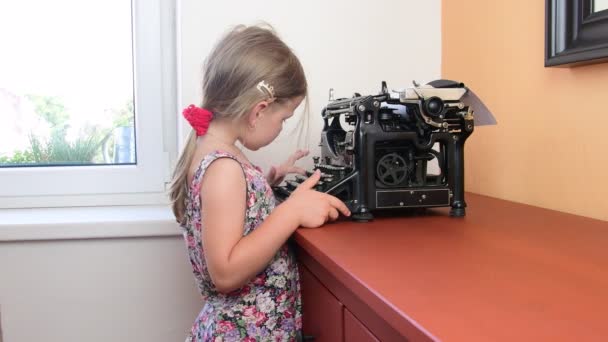 Doce menina escreve na máquina de escrever vintage. Conceito pré-escolar, conceito infantil. Menina bonito como pré-escolar — Vídeo de Stock