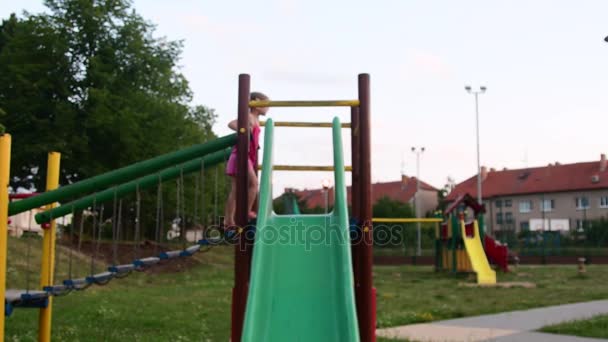 View of girl goes on rope bridge in the playset at playground. Girl on the slide at playground. Low DOF — Stock Video