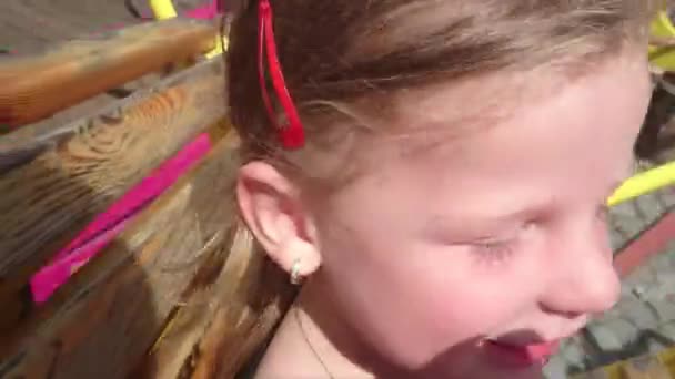 Söt liten flicka på nöjesfält attraktion. Funfair karusell. Närbild av vackra glad tjej att ha kul ridning karusell i nöjesparken. — Stockvideo