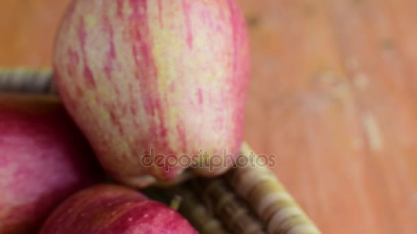 Κόκκινα μήλα σε ψάθινο καλάθι σε καφέ φόντο. Περιστρεφόμενο μήλα. Κινηματογράφηση σε πρώτο πλάνο — Αρχείο Βίντεο