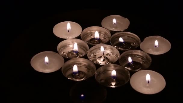 Tea light candles rotating on a mirror background. Side view — Stock Video