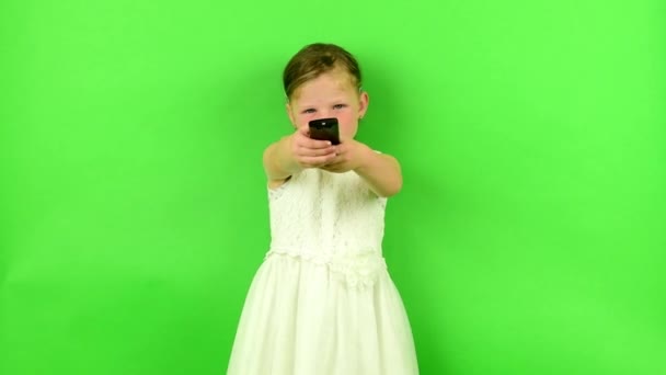 La fille utilise la télécommande. Petite fille sur fond chromatique clé . — Video