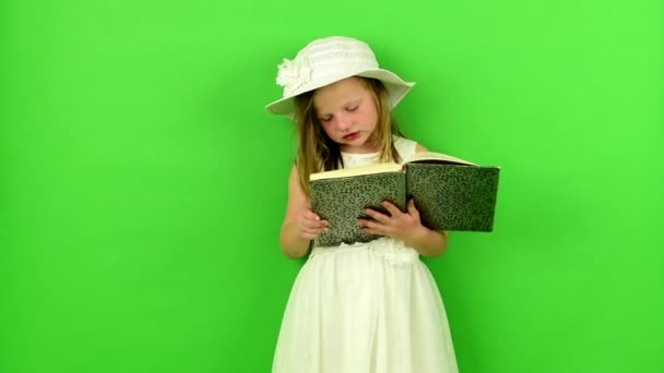 La fille lit le livre. Petite fille sur fond chromatique . — Video