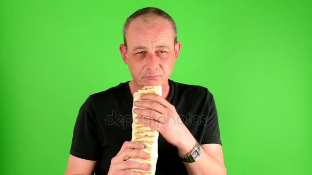 Hombre maduro de mediana edad. Retrato de un hombre maduro come la comida rápida - kebab también llamado giroscopios en frente de la pantalla verde . — Vídeo de stock