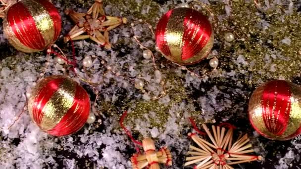 Vánoční dekorace. Vánoční koule, zlaté vločky a vločky na černém pozadí. — Stock video