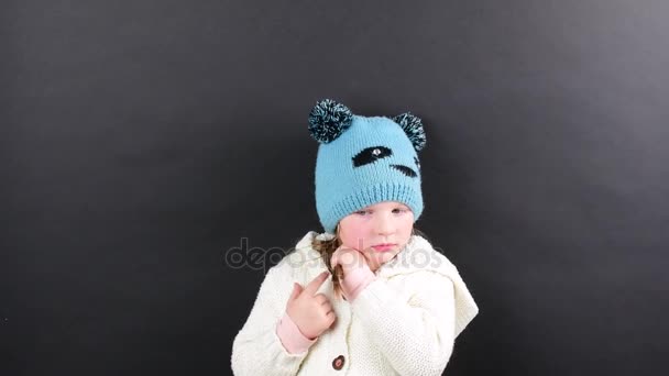 Kleines Mädchen trägt Winterkleidung. niedliches kleines Mädchen auf schwarzem Hintergrund. — Stockvideo