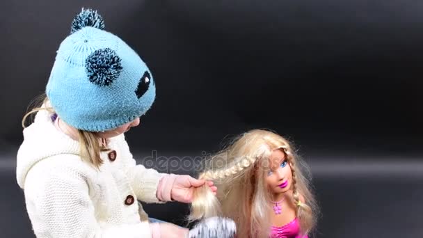 Nettes Mädchen kämmt Styling-Kopf. Kleines Mädchen trägt Winterkleidung. niedliches kleines Mädchen auf schwarzem Hintergrund. — Stockvideo
