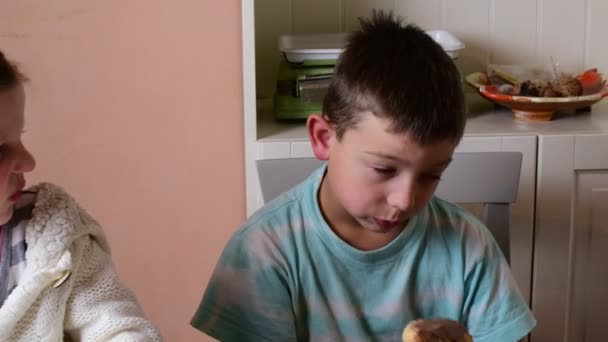 Menino e menina pequena têm um lanche. Os irmãos comem creme de chocolate espalhado no rolo. Conceito familiar . — Vídeo de Stock