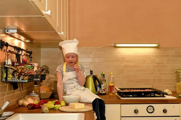 Милая маленькая девочка готовит на сельской кухне. Маленькая девочка готовит пиццу . — стоковое фото