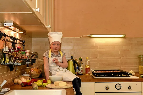 Niña con sombrero de chef dentro de la cocina. Niña prepara pizza . — Foto de Stock