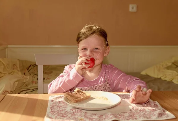 La fillette mange de la crème au chocolat sur du pain. Snack au chocolat sucré. Bonne fille a une collation dans la cuisine. Une jolie petite fille sourit. Une petite fille avec des taches de crème au chocolat sur le visage. Ludique — Photo