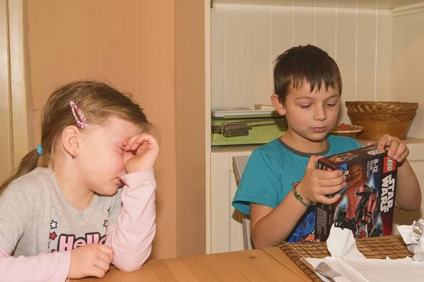 Boy celebrating the ninth birthday. The birthday present is LEGO Star Wars. Brother and his disappointed sister. — Stock Photo, Image
