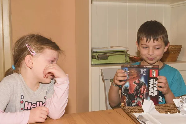 Chłopiec obchodzi urodziny. Prezent urodzinowy jest Lego Star Wars. Brat i jego siostra rozczarowany. — Zdjęcie stockowe