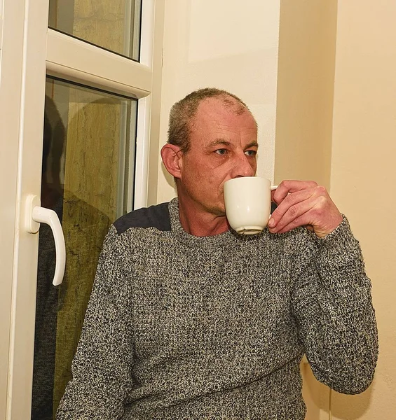 Homem de meia-idade deprimido sentado perto da janela. Triste homem bebendo café — Fotografia de Stock