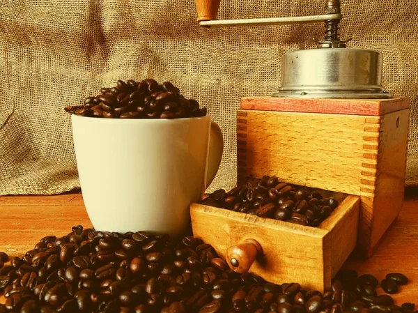 Molino de café vintage, granos de café y granos de café rellenos de taza blanca sobre fondo de madera — Foto de Stock