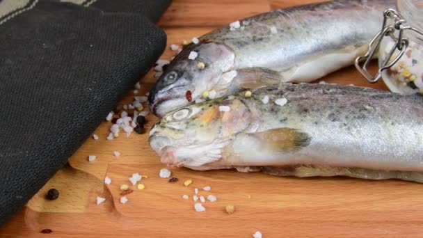 Fresh raw rainbow trouts with spices on wooden board. Healthy food and dieting concept. Close-up — Stock Video