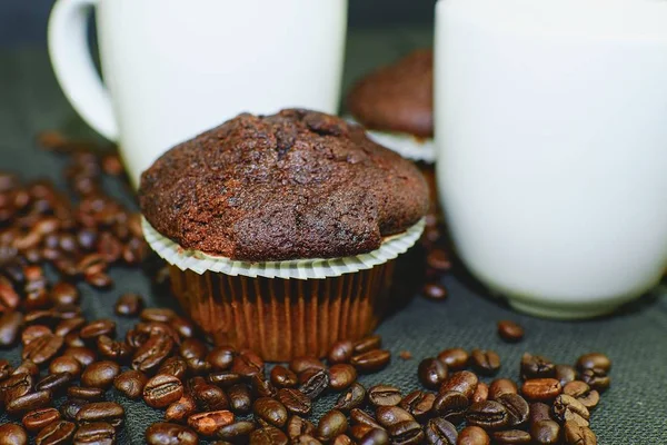 Σκούρο muffins, φλιτζάνια καφέ και κόκκους καφέ σε μαύρο φόντο. — Φωτογραφία Αρχείου