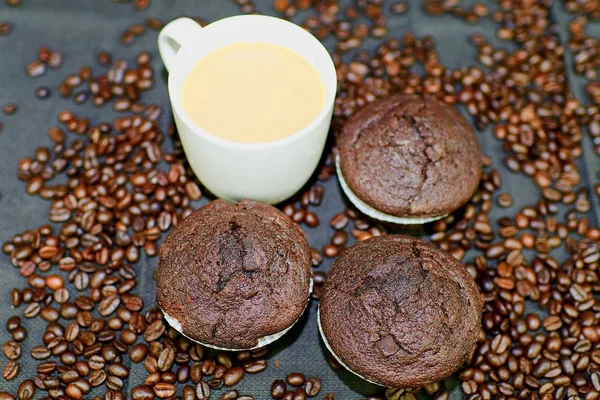 Muffin scuri, tazze di caffè e chicchi di caffè su sfondo nero. Design piatto. Concetto bar — Foto Stock