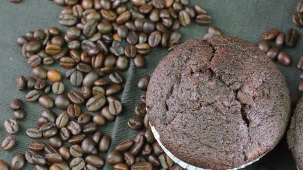 Muffins escuros e grãos de café em fundo preto . — Vídeo de Stock