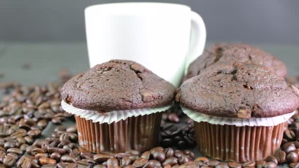 Dunkle Muffins, Tasse Kaffee und Kaffeebohnen auf schwarzem Hintergrund — Stockvideo
