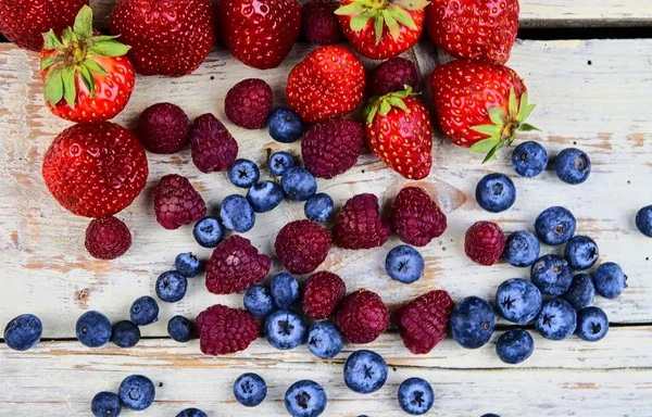 Friska blandad frukt och ingredienser med jordgubb, hallon, blåbär från ovanifrån. Bär på rustik vit trä bakgrund — Stockfoto