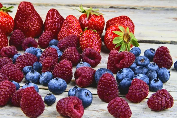 Frutta mista sana e ingredienti con fragola, lampone, mirtillo. Bacche su fondo rustico in legno bianco. Primo piano. Immagine macro — Foto Stock