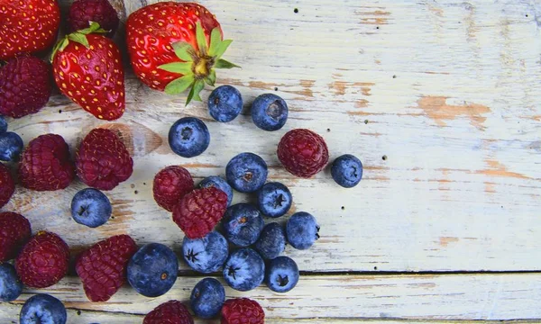 健康的混合水果和配料与草莓, 覆盆子, 蓝莓从顶部的看法。在质朴的白色木质背景浆果。平面设计。文本的可用空间。为横幅复制空间 — 图库照片