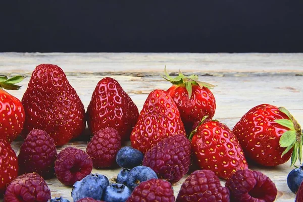 Egészséges vegyes gyümölcsök és összetevők, eper, málna, áfonya. Bogyók, rusztikus, fehér, fából készült háttér. Szabad hely, a szöveg. Másolja a hely a banner — Stock Fotó