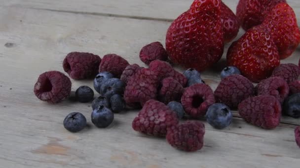 Fruta sana mezclada e ingredientes con fresa, frambuesa, arándanos. Bayas sobre fondo rústico de madera blanca — Vídeo de stock