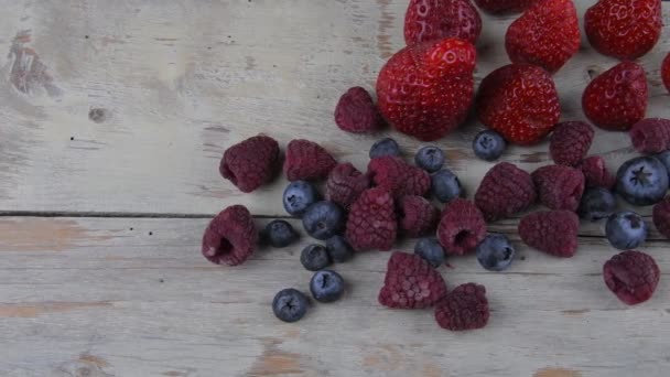 Fruta sana mezclada e ingredientes con fresa, frambuesa, arándanos. Bayas sobre fondo rústico de madera blanca — Vídeos de Stock