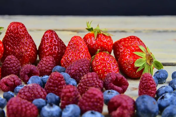 Friska blandad frukt och ingredienser med jordgubb, hallon, blåbär. Bär på rustik vit trä bakgrund. Ledigt utrymme för text. Kopiera utrymme för banner — Stockfoto