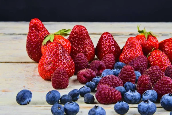 Gezonde vruchtenmengsels en ingrediënten met aardbei, framboos, bosbes. Bessen op rustieke witte houten achtergrond. Vrije ruimte voor tekst. Ruimte voor banner kopiëren — Stockfoto