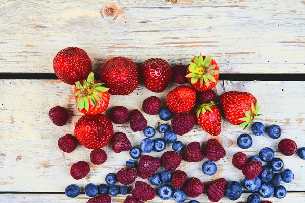 健康的混合水果和配料与草莓, 覆盆子, 蓝莓从顶部的看法。在质朴的白色木质背景浆果。平面设计。文本的可用空间。为横幅复制空间 — 图库照片