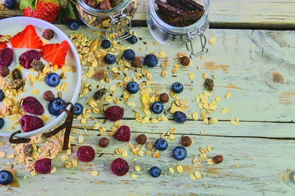 Composition of a typical genuine breakfast made with yoghurt, blueberries, raspberries, blueberries, muesli. Concept of: fitness, diet, wellness and breakfasts. Flat design. Top view