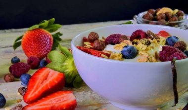 Sağlıklı kahvaltı, yoğurtlu tahıl gevreği, çilek, yabanmersini, ahududu ve müsli ahşap arka planda. Konsept: fitness, diyet, sağlık ve kahvaltı