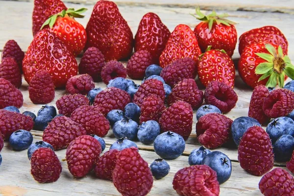 Egészséges vegyes gyümölcsök és összetevők, eper, málna, áfonya. Bogyók, rusztikus, fehér, fából készült háttér. Közelről. Makró kép — Stock Fotó