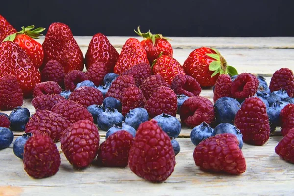 Gezonde vruchtenmengsels en ingrediënten met aardbei, framboos, bosbes. Bessen op rustieke witte houten achtergrond. Vrije ruimte voor tekst. Ruimte voor banner kopiëren — Stockfoto