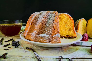 Eski ahşap arka plan üzerinde siyah çay ve adet vanilya kupa ile kum pasta moda. Rustik beyaz zemin üzerine stawberries ile yumurta sarısı sünger kek.