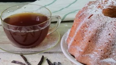 Eski ahşap arka plan üzerinde siyah çay ve adet vanilya kupa ile kum pasta moda. Rustik beyaz zemin üzerine stawberries ile yumurta sarısı sünger kek