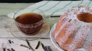 Eski ahşap arka plan üzerinde siyah çay ve adet vanilya kupa ile kum pasta moda. Rustik beyaz zemin üzerine stawberries ile yumurta sarısı sünger kek