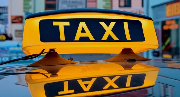 Lit taxi sign on roof of taxi car in the city