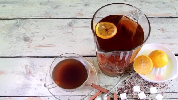 Chá preto, espremedor manual com limões. Um jarro de chá preto e cubos de açúcar . — Vídeo de Stock